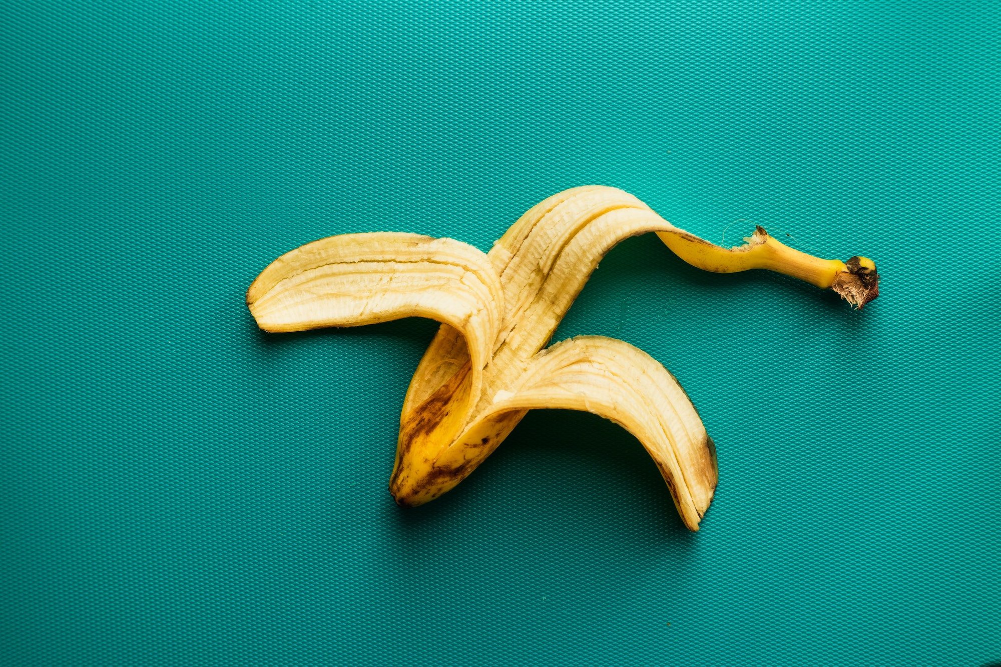 empty banana peel on teal background