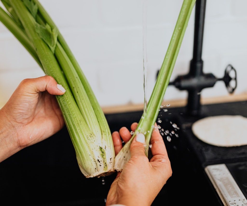 Person washing celery in a sink
