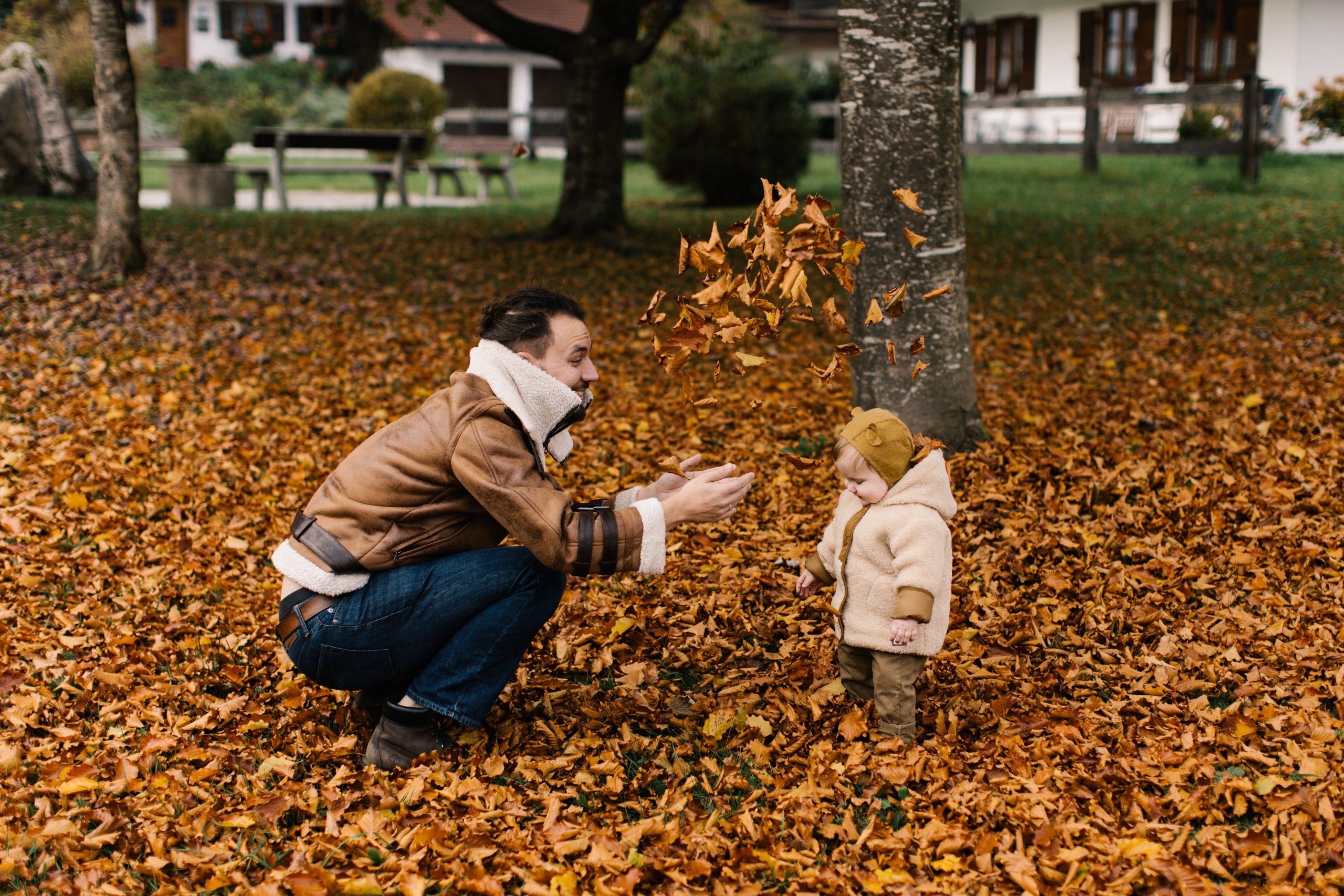Man playing with his child outside during fall