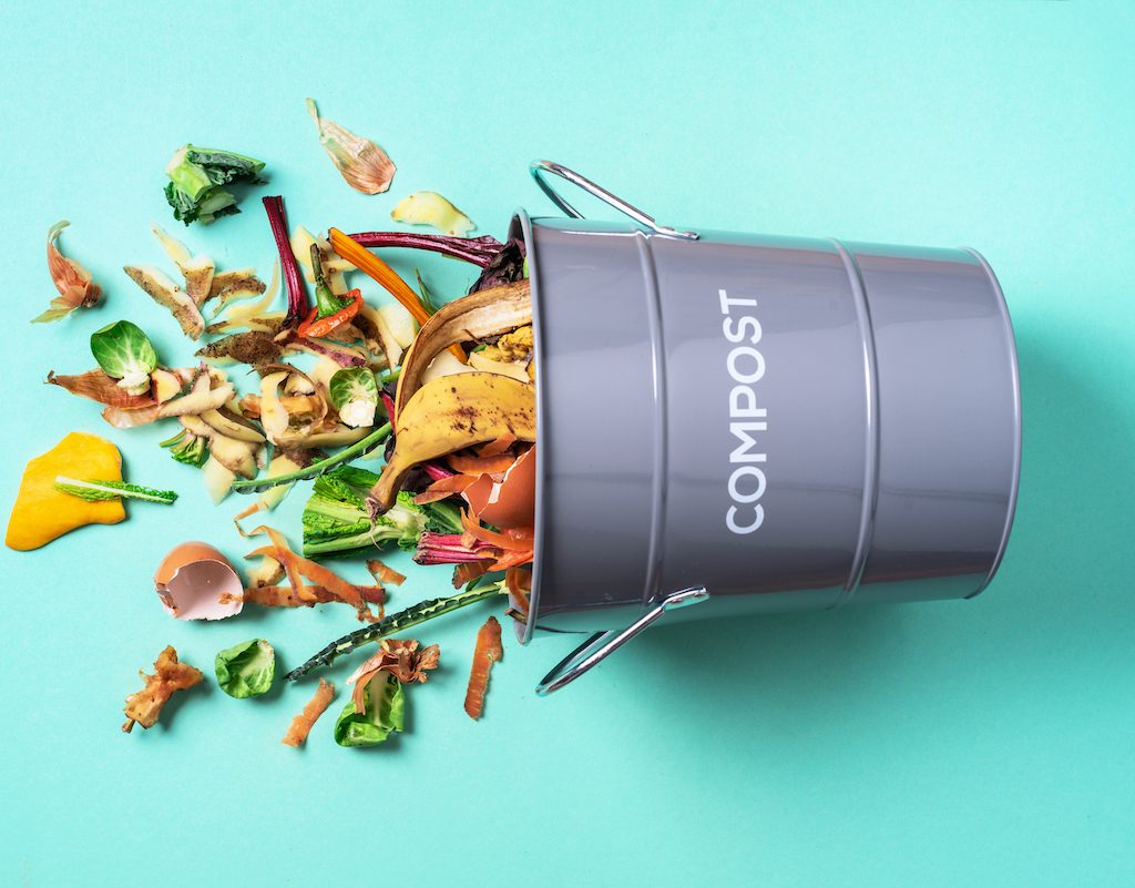 A metal bucket on its side with food scraps spill out of it