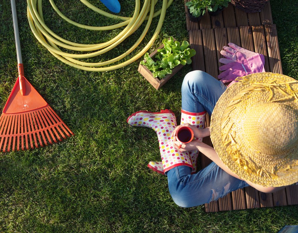 overhead view of woman sitting on grass with garden tools