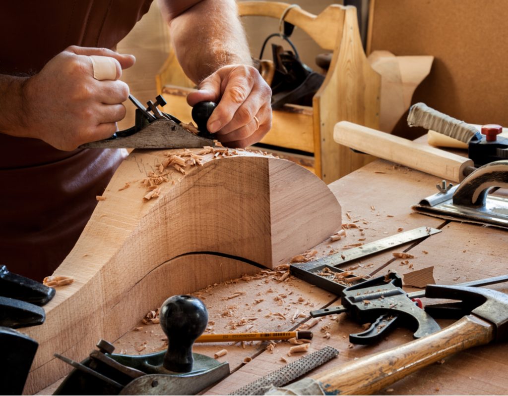 Man carving a new leg for a chair out of wood