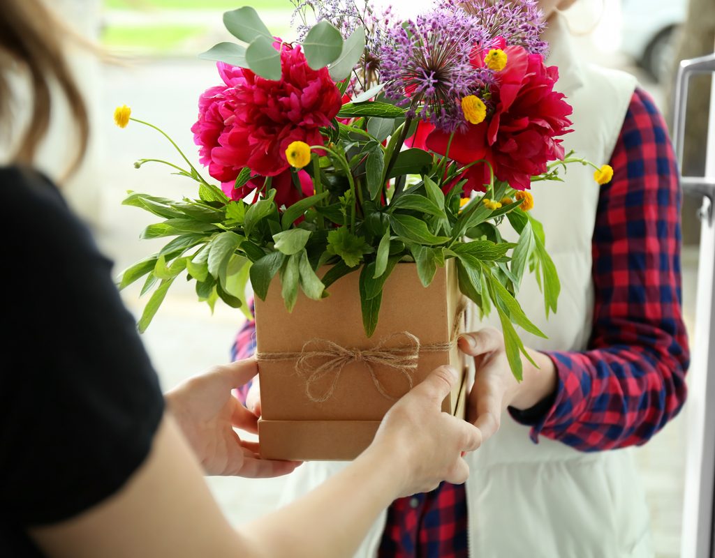 someone presenting a flower arrangement to someone else