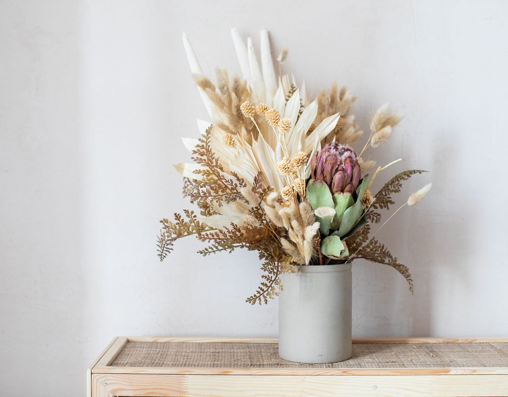 An arrangement of dried flowers in a light gray vase