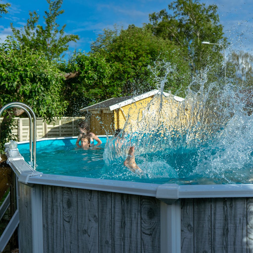 Family jumping into an above-ground pool