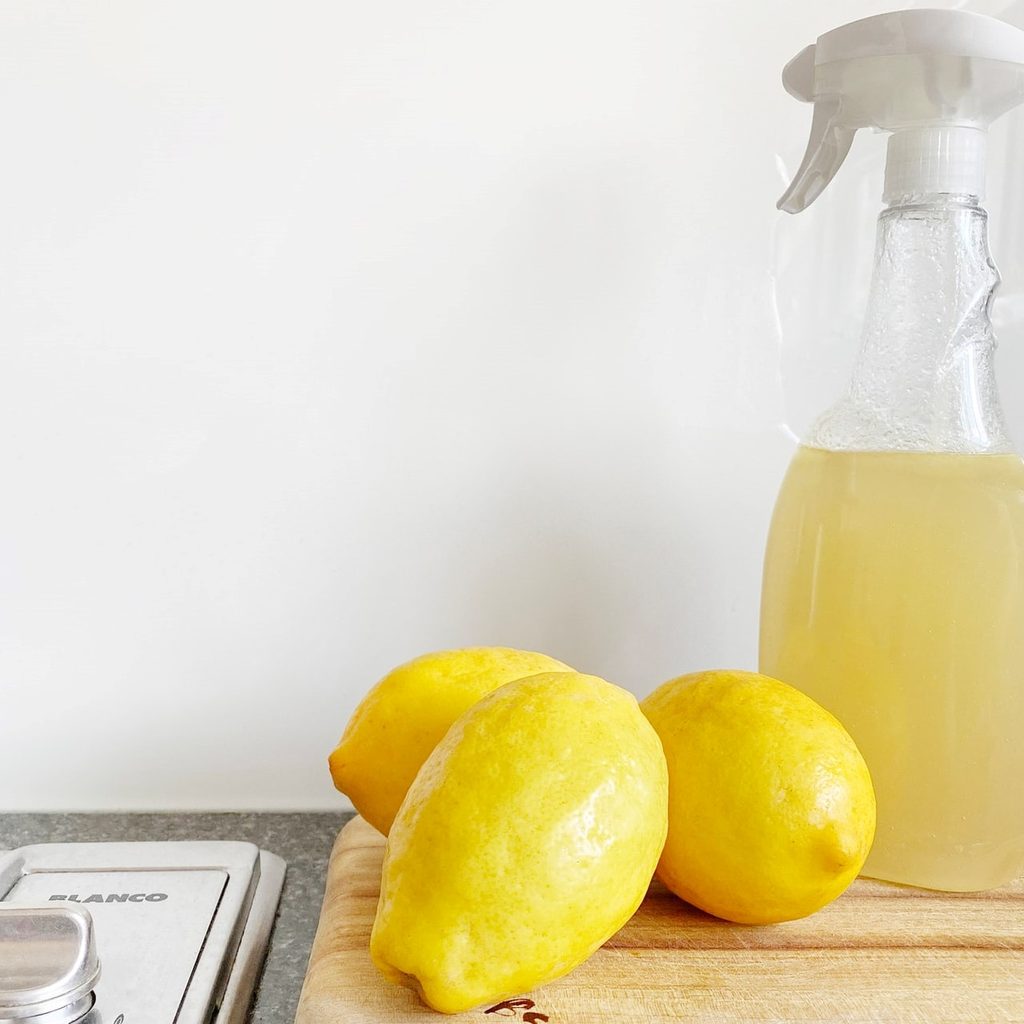 Lemons sitting next to a spray bottle full of lemon and vinegar