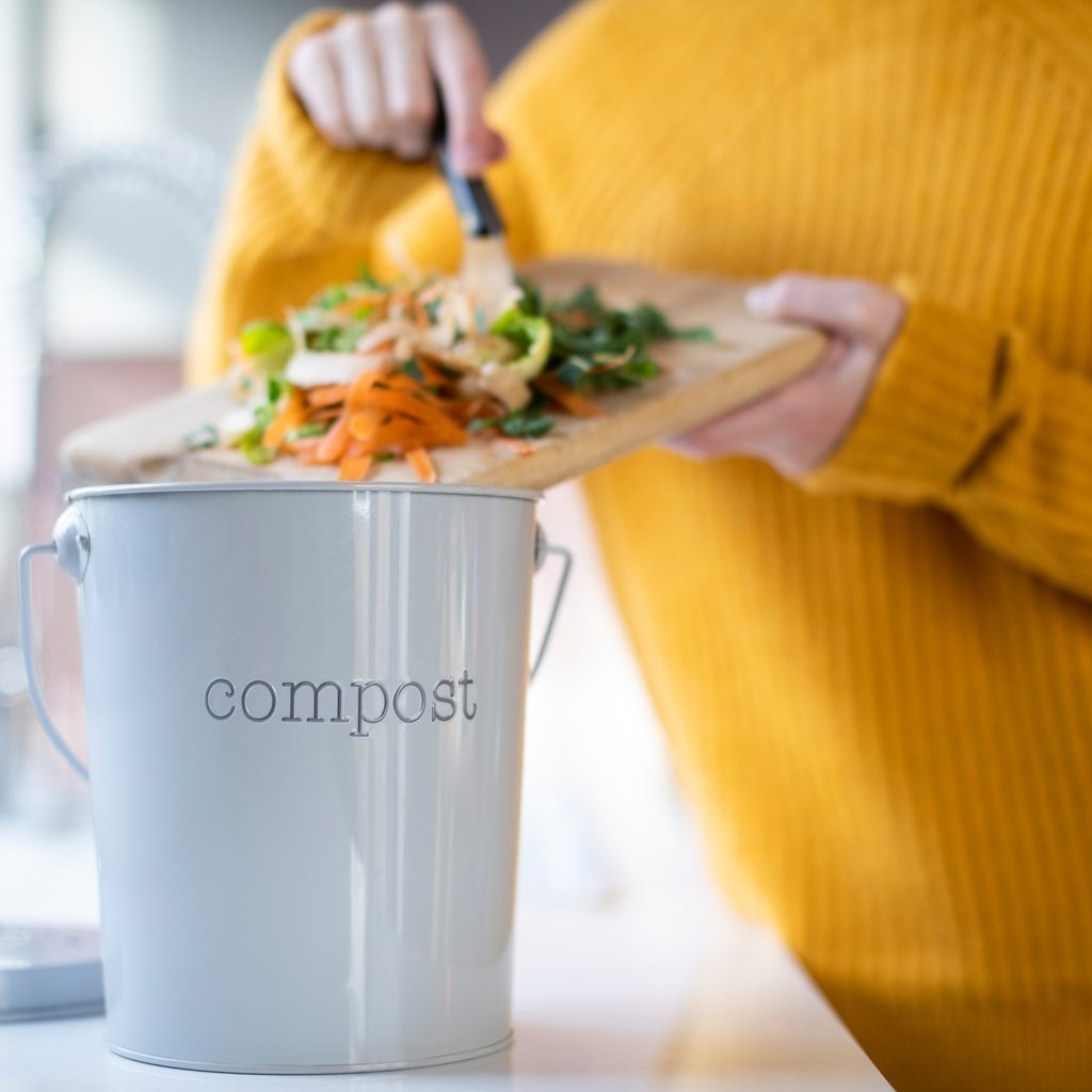 Person adding vegetable scraps to a compost container