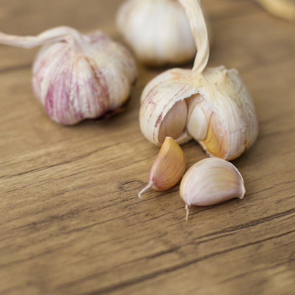 Three garlic bulbs with some garlic cloves next to them