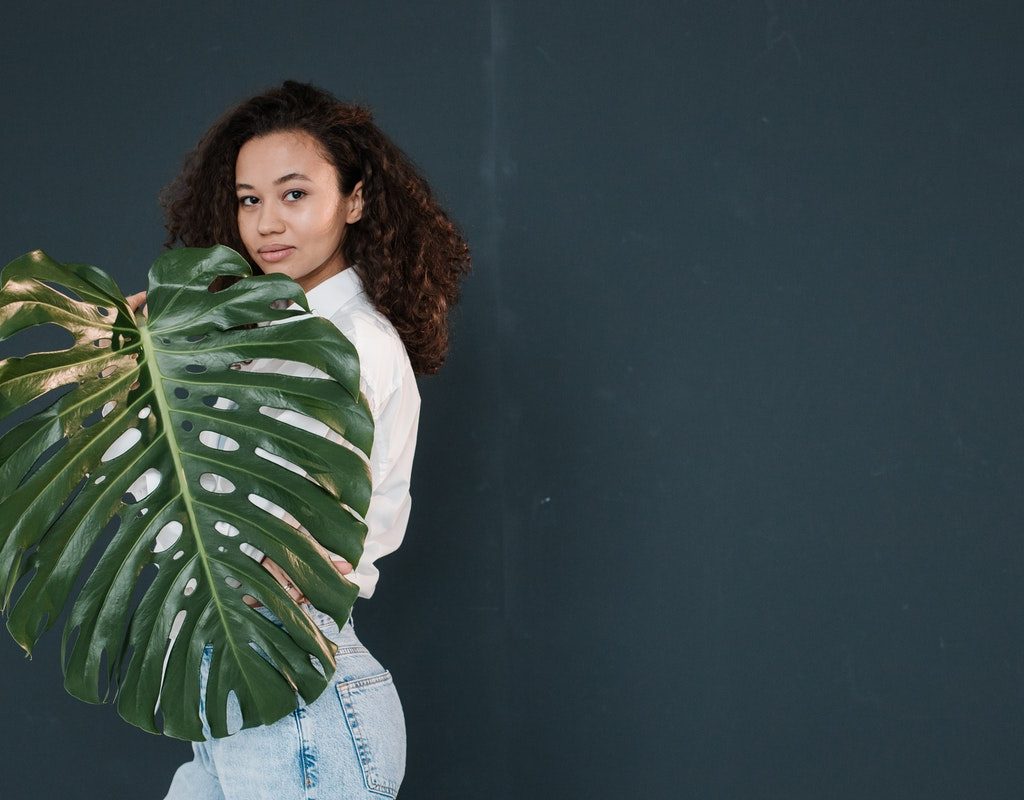 A woman posing with a large monstera leaf