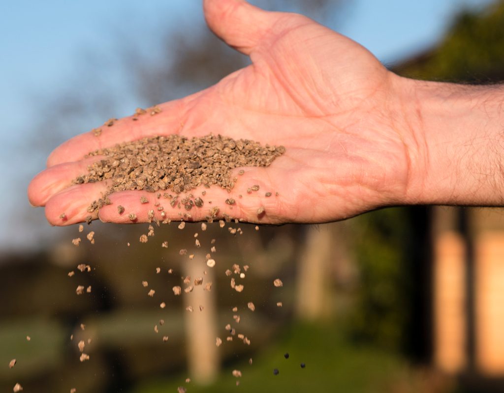 A hand holding and scattering bone meal