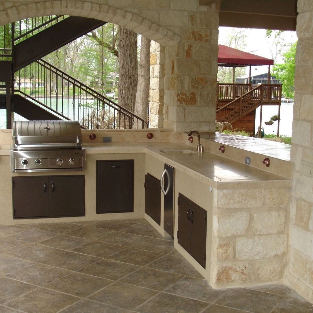 Outdoor kitchen with stone countertop and floor