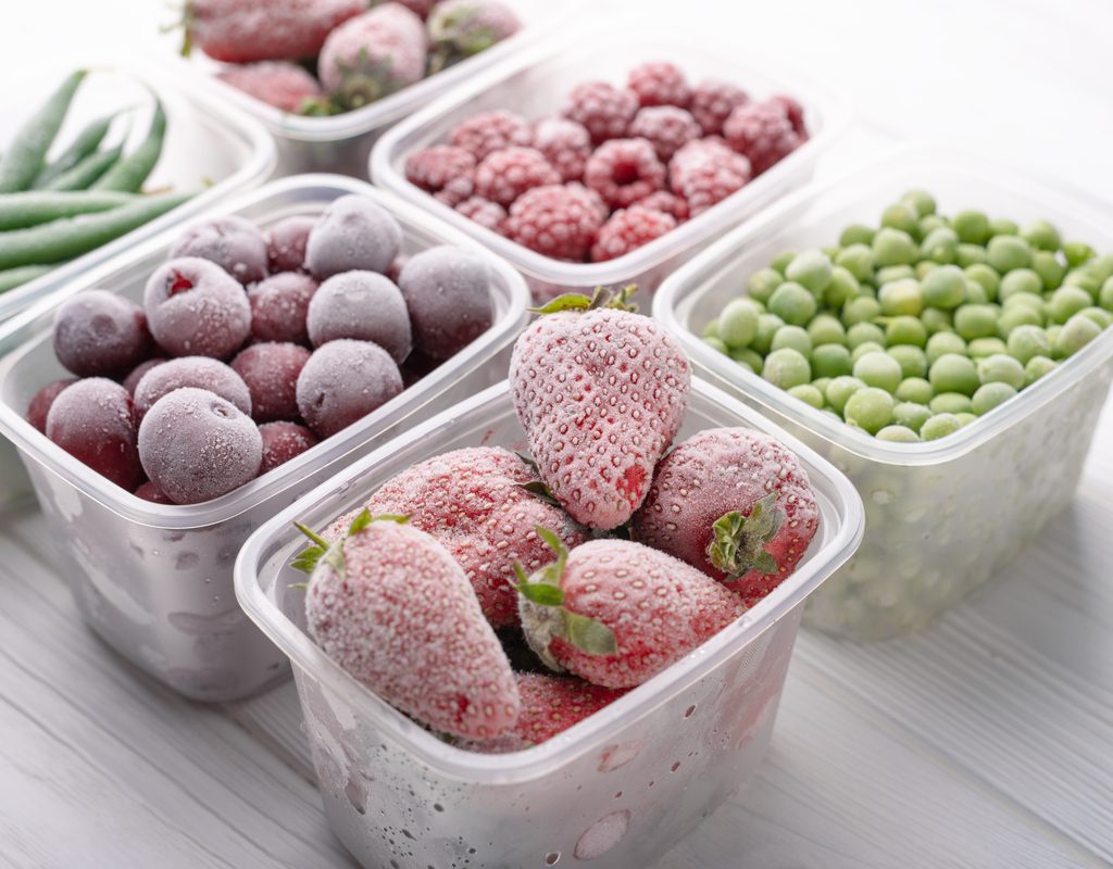 An assortment of frozen fruits and vegetables in clear plastic containers