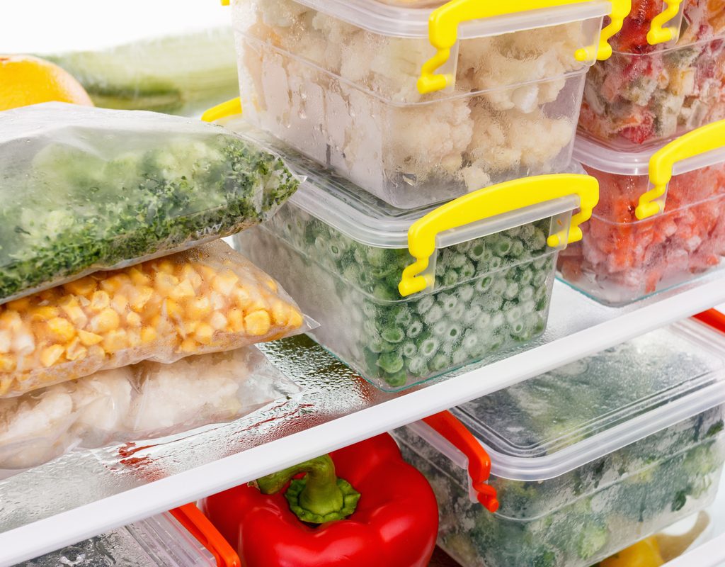 Various frozen vegetables stored in plastic containers and bags