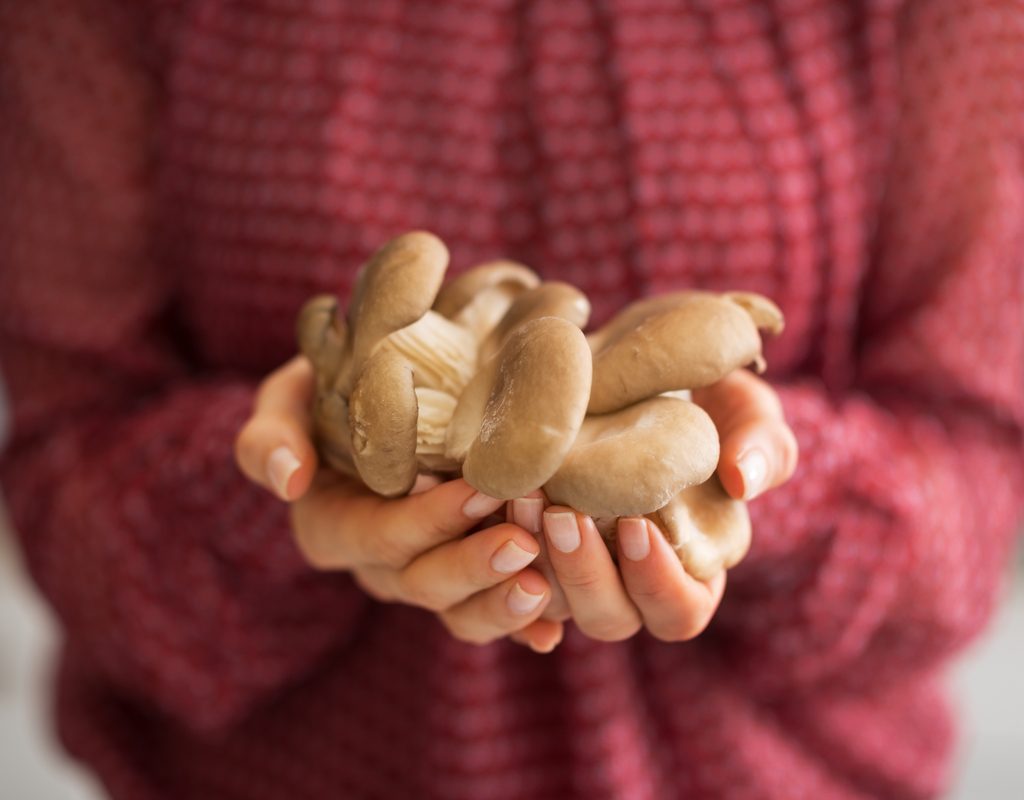 A young woman holding a handful of oyster mushrooms