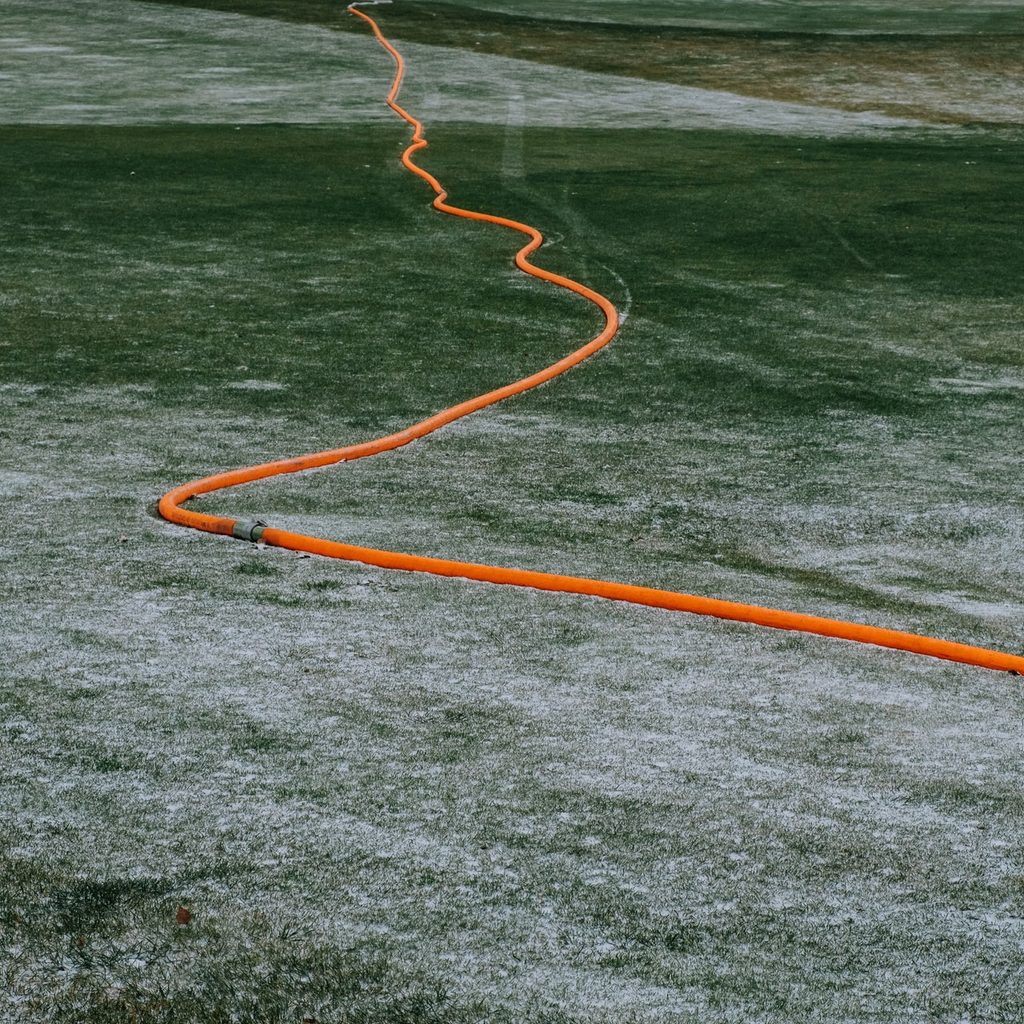 orange hose on frosty grass