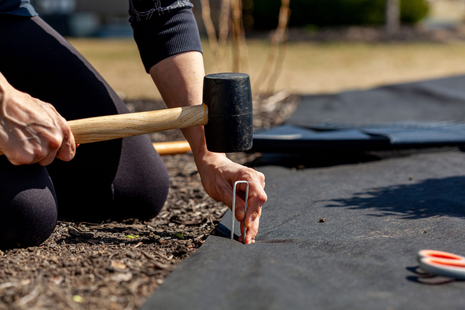 Person installing stake in landscape fabric