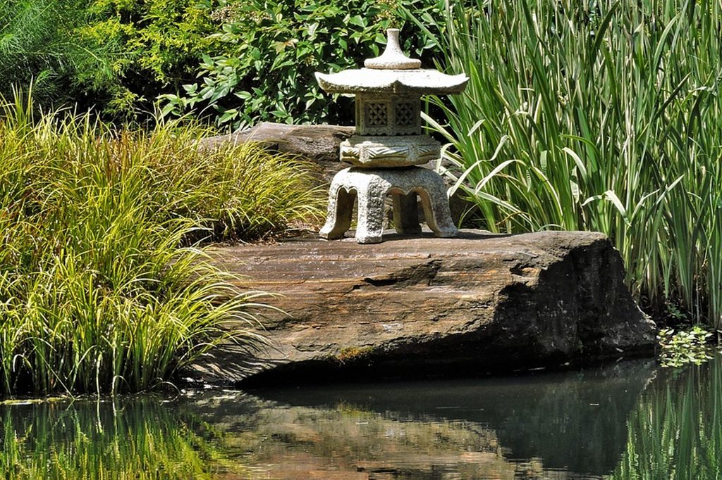 A zen garden pond with a small pagoda statue