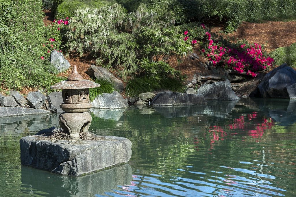 A zen garden pond with a small pagoda statue