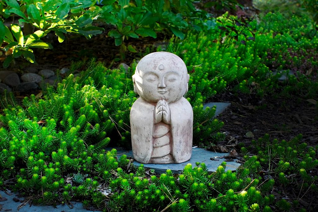 A small Buddha statue in a zen garden