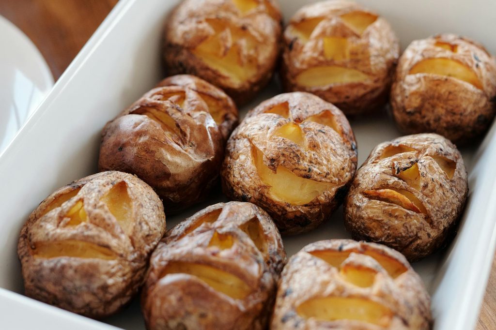 Potatoes with jack-o-lantern faces carved into them in a baking dish