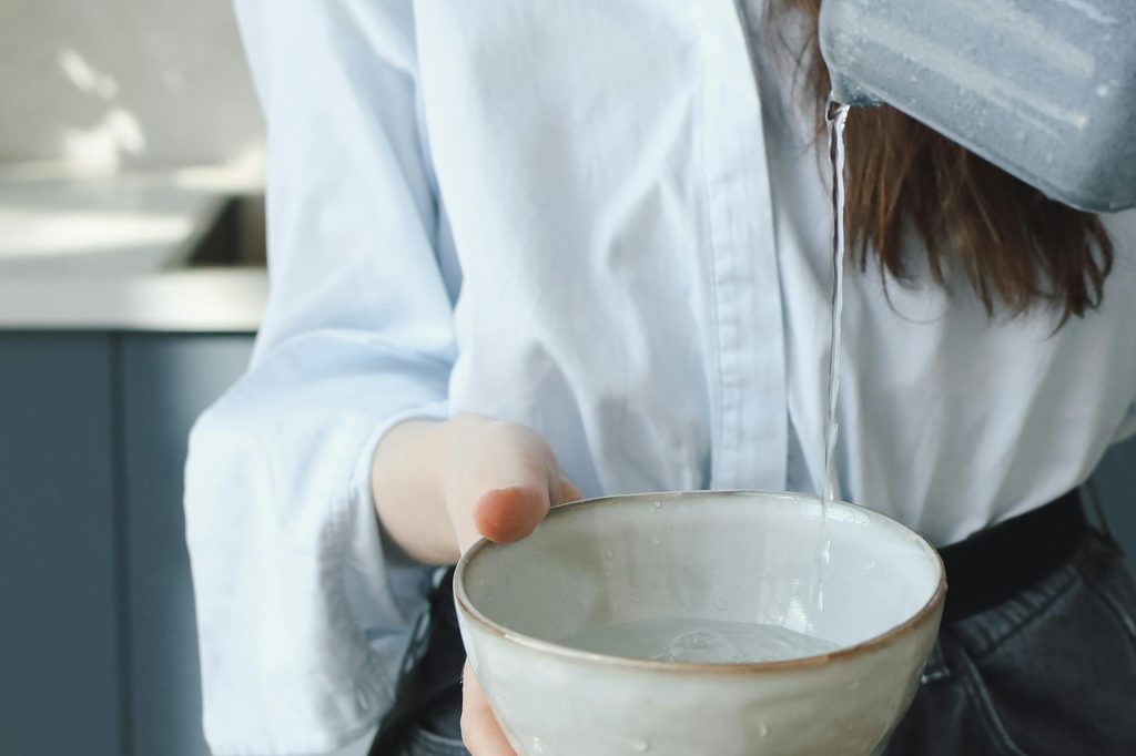 A woman pouring water into a ceramic bowl