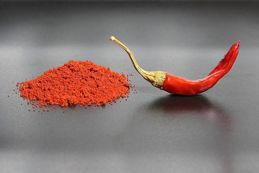 A dried red pepper and a pile of paprika