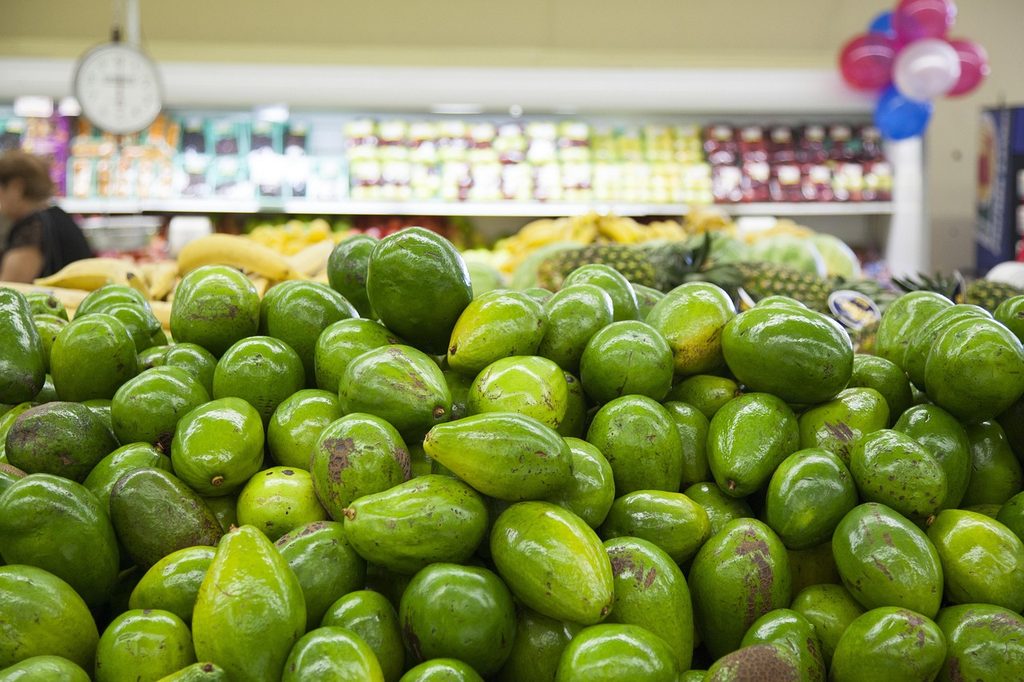 A grocery store display of avocados