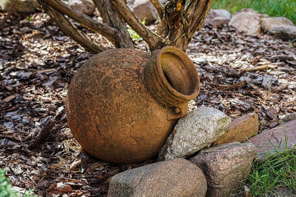 A garden border make of rocks with a decorative pitcher next to it