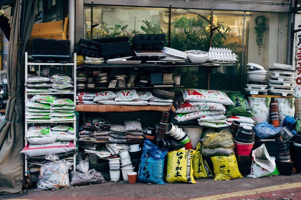 An outdoor shelf with fertilizer, soil, and flower pots
