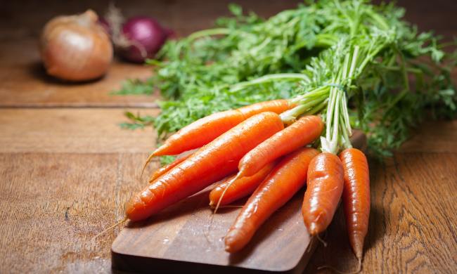 Clean carrots on a wooden cutting board