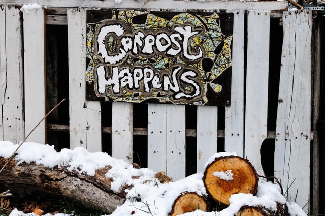 Snowy logs with a sign reading "compost happens"