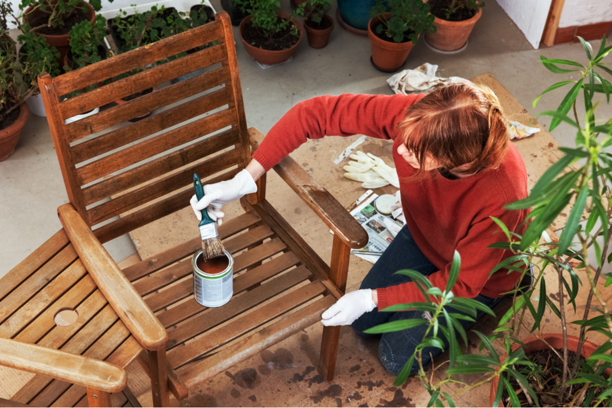 A person staining a wooden chair