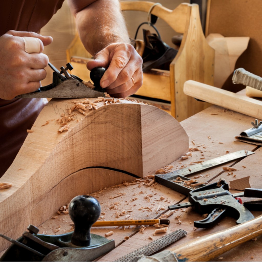 Man carving a new leg for a chair out of wood