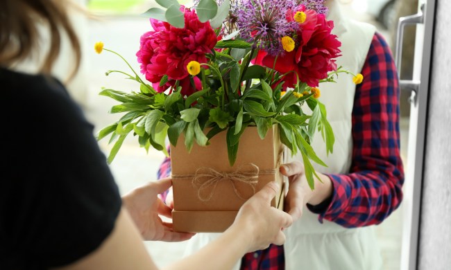Someone presenting a flower arrangement to someone else
