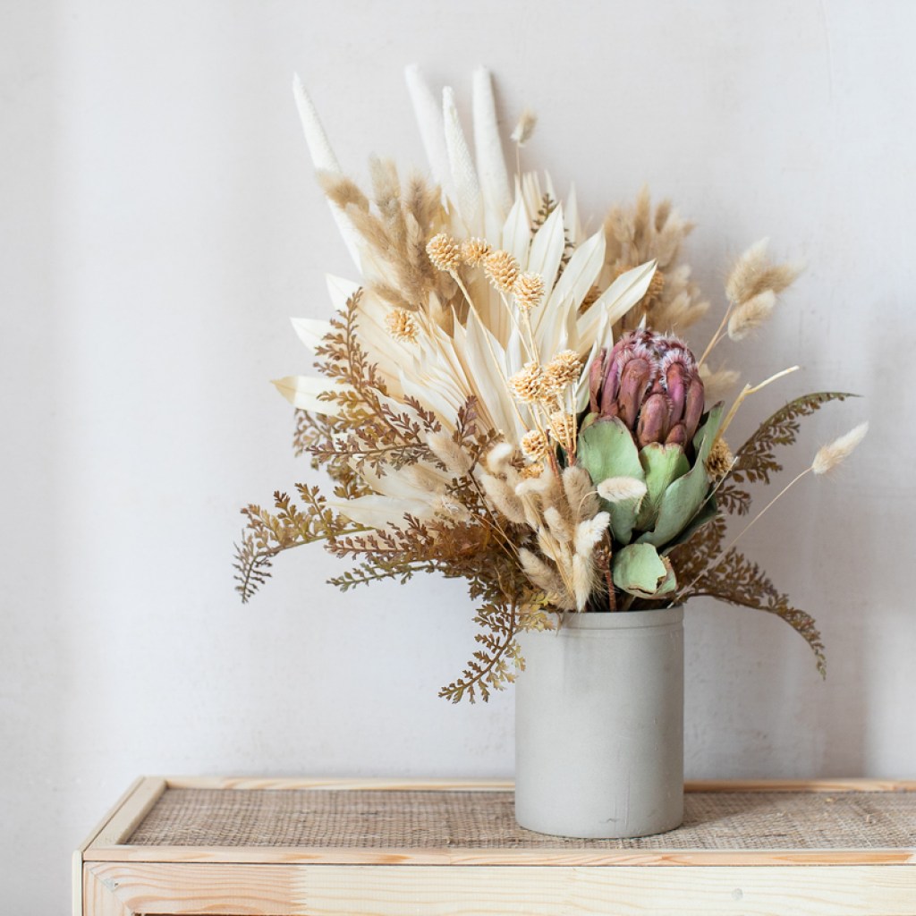 An arrangement of dried flowers in a light gray vase