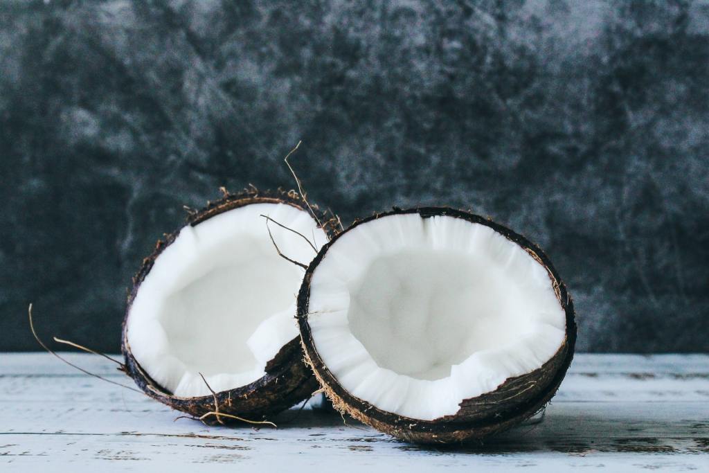 Coconut fruit split in half in front of black marble background