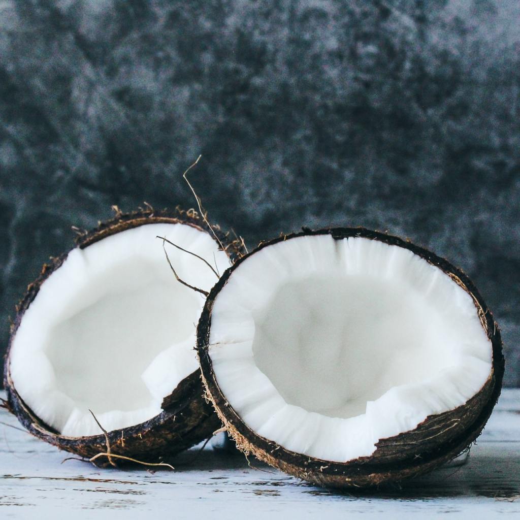 Coconut fruit split in half in front of black marble background