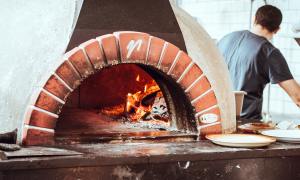 Man making pizza in wood fire oven