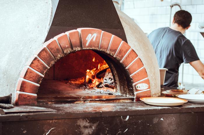 Man making pizza in wood fire oven