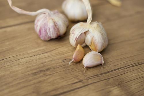 Three garlic bulbs with some garlic cloves next to them