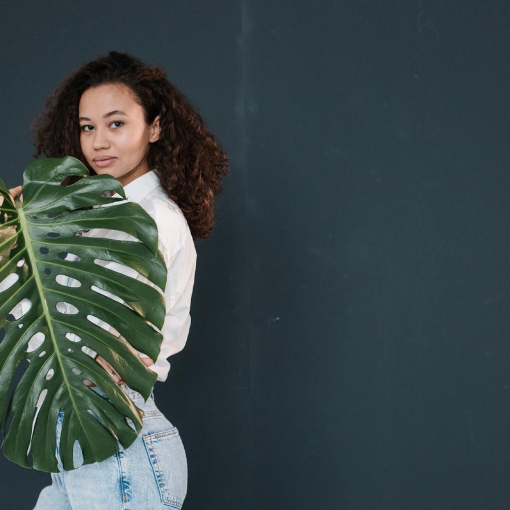 A woman posing with a large monstera leaf
