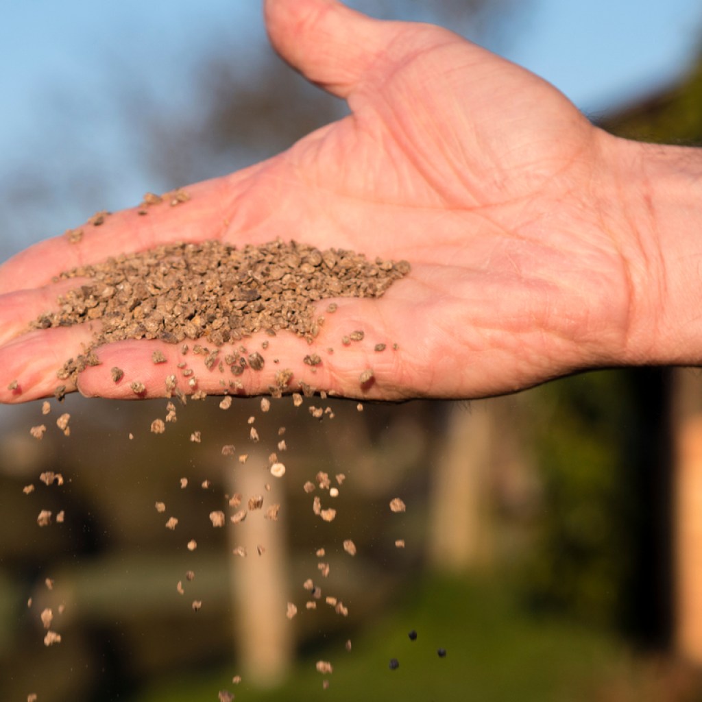 A hand holding and scattering bone meal