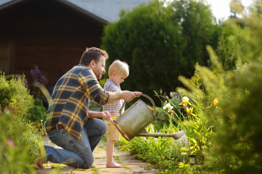 Father teaching child how to water the garden.