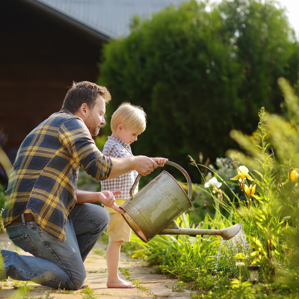 Father teaching child how to water the garden.