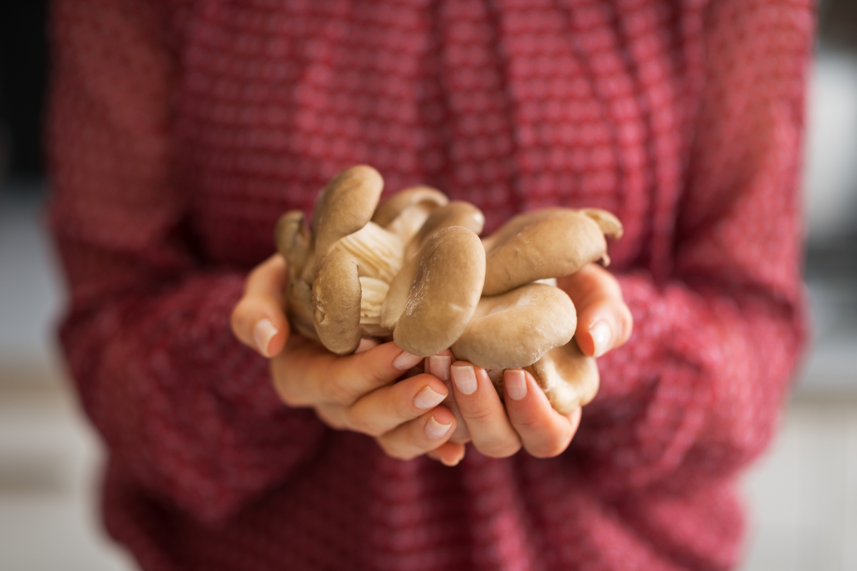 A young woman holding a handful of oyster mushrooms