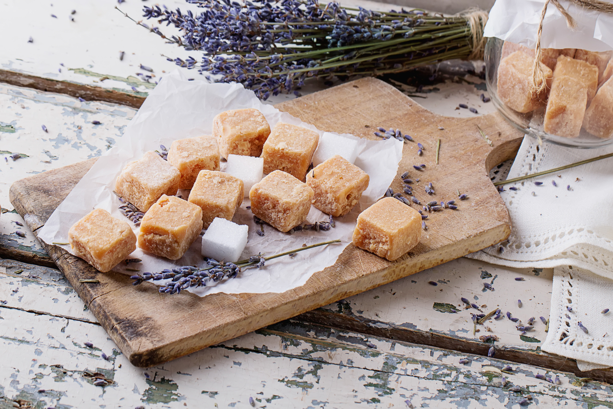 Several lavender caramels on a wooden cutting board