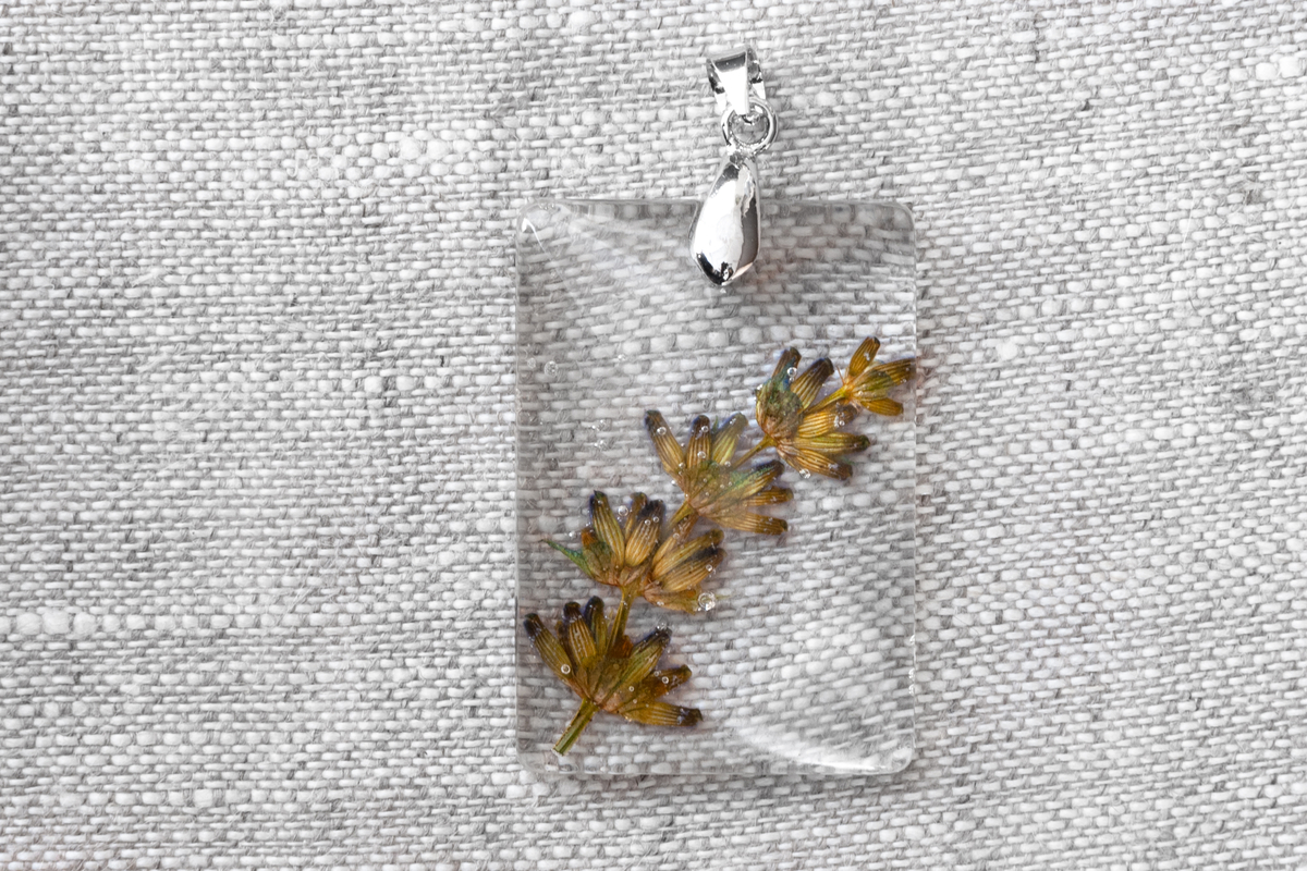 A small clear resin pendant with a sprig of dried lavender in the middle