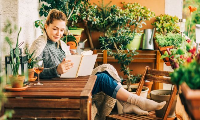Woman reading book by plants