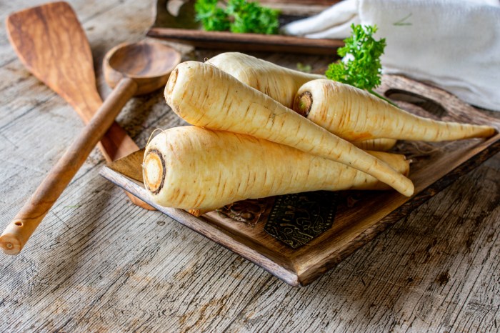 Several raw parsnips on a wooden plate