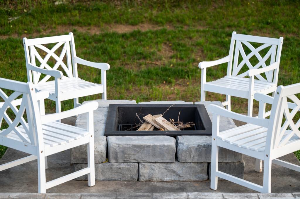 Square fire pit with white chairs around it